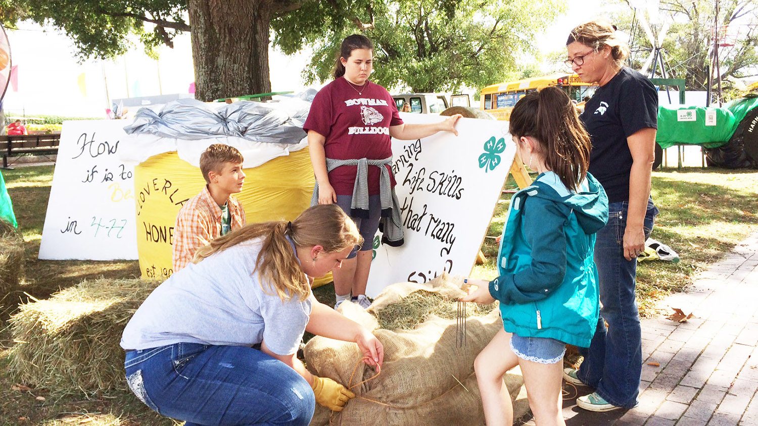 With the help of their 4-H agent and volunteer, Mitchell County 4-H'ers decorate hay bales at the State Fair.