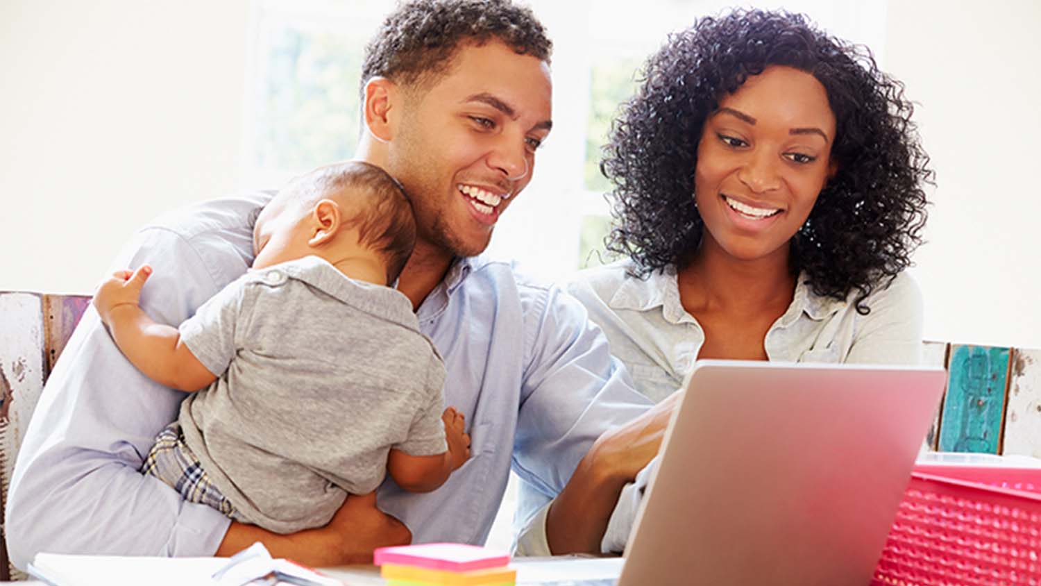 Parents holding a baby looking at a laptop