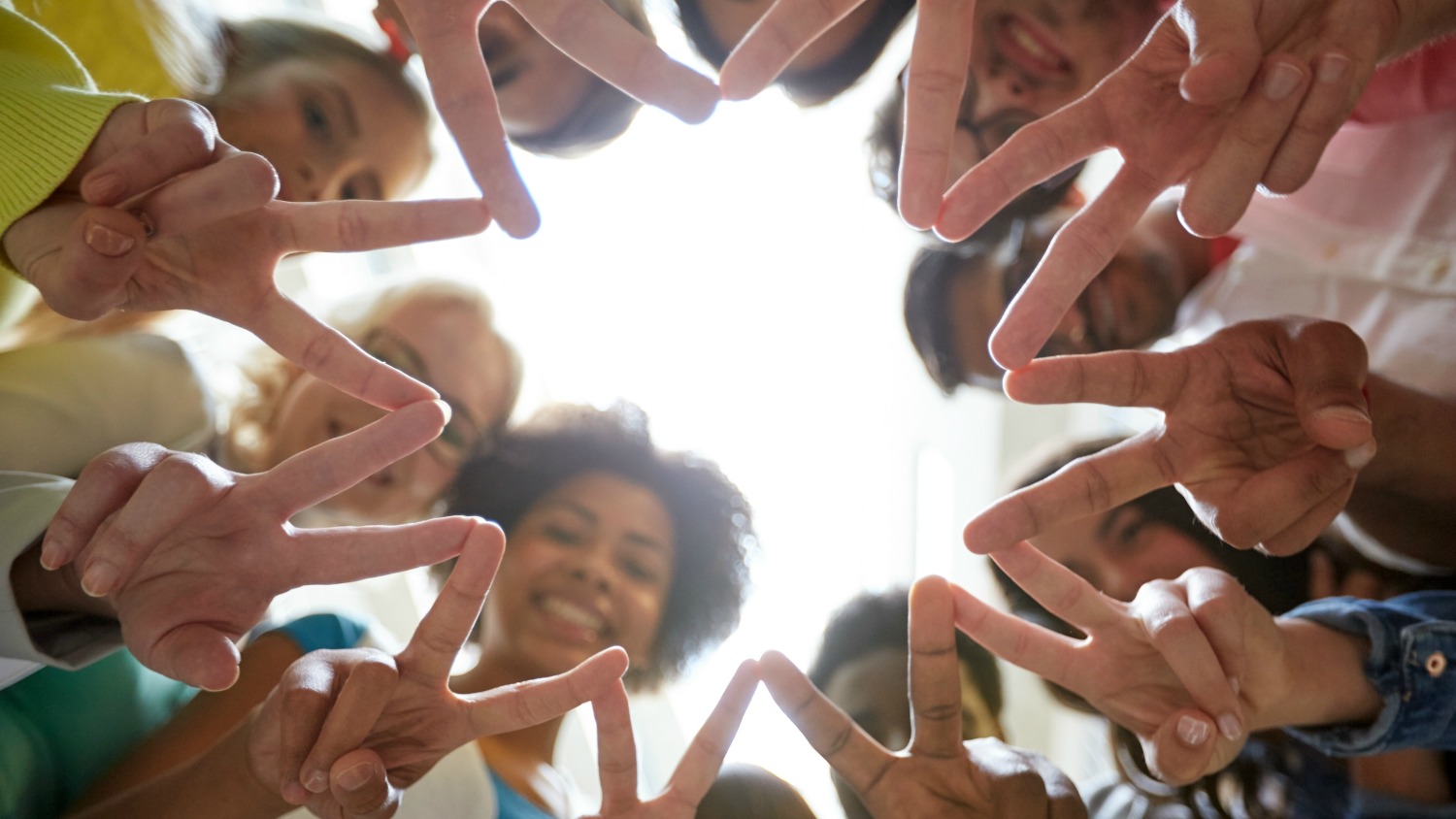 diverse people in a circle with peace signs.