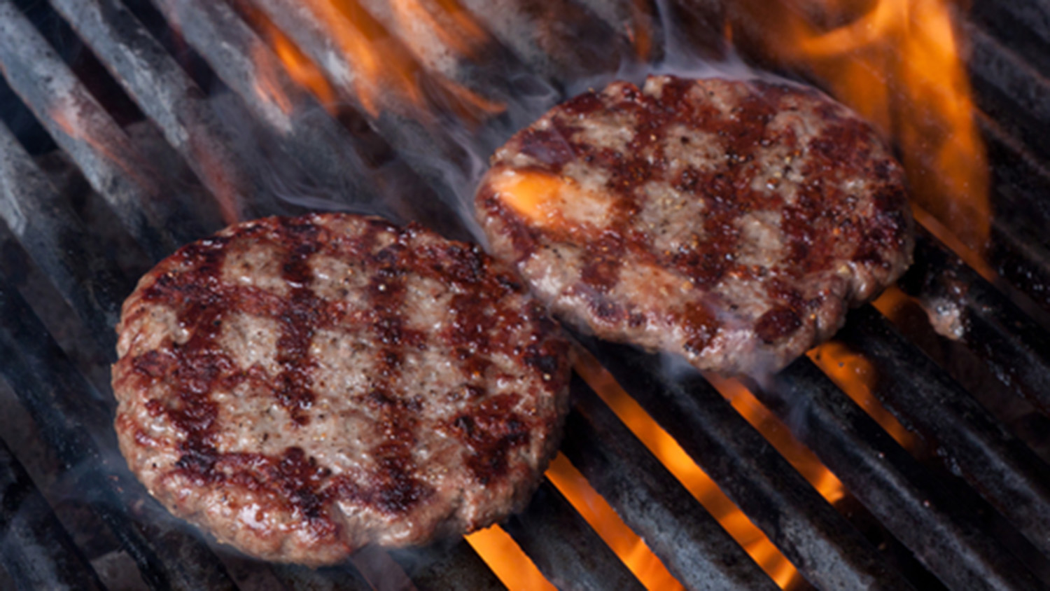 Two hamburgers cooking on a grill