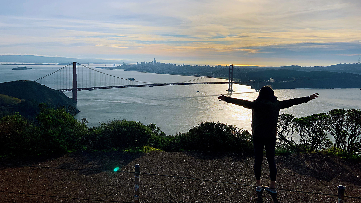 Alice Chen standing on top of a hill overlooking a bridge and water.