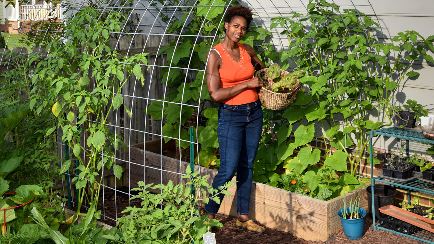 A young black woman in a garden holding a basket