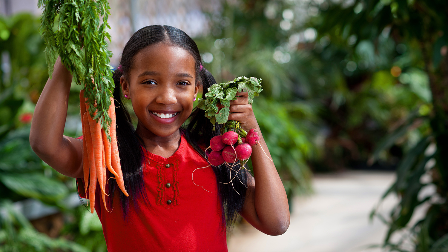 YFCS graduate student Crystal Starkes, holds fresh grown carrots (right-hand), and fresh strawberries (left-hand)