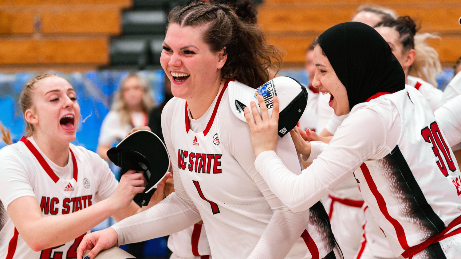 NC State center River Baldwin smiles as teammates congratulate her
