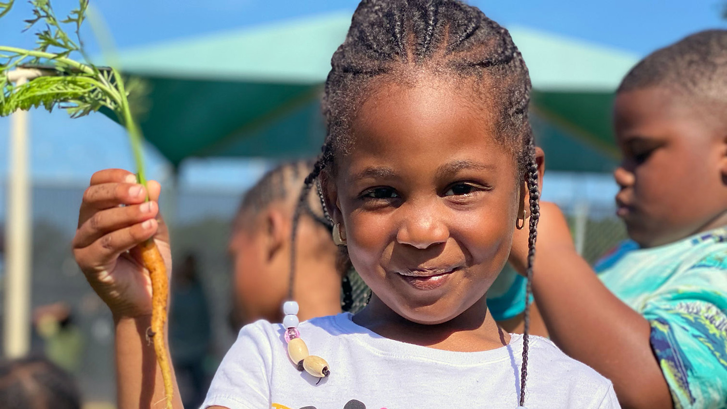 A preschool student holds a carrot