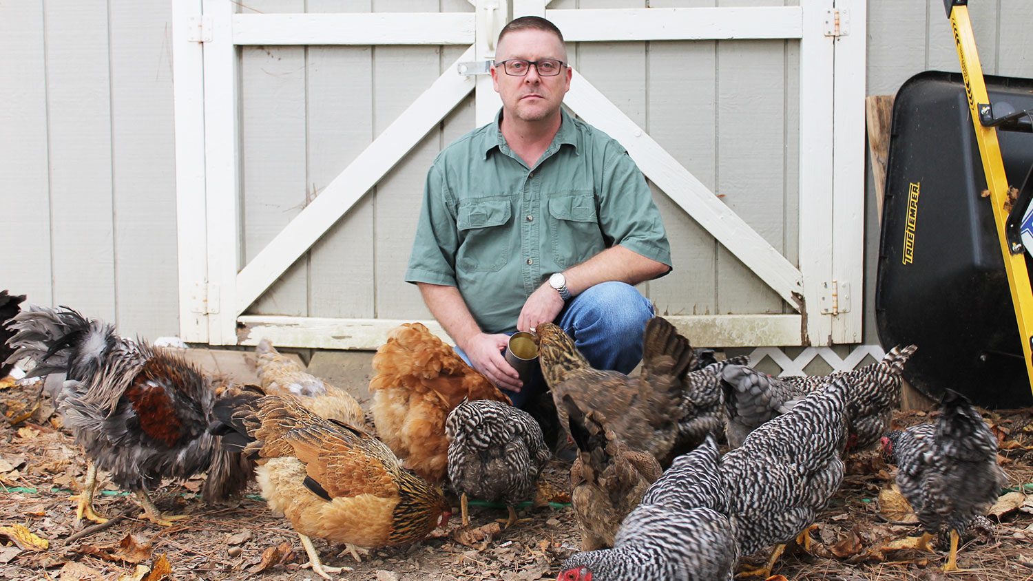Farmer in front of a barn with several chickens