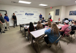 Group gives presentation in room with "Fastenal Service Standards" on the wall