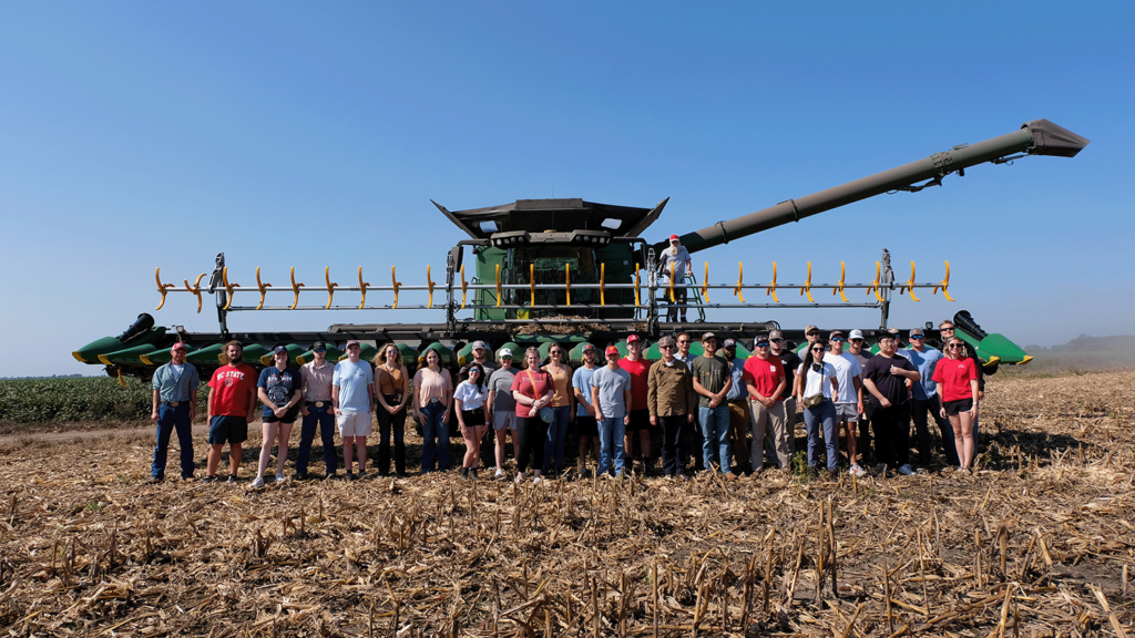 students standing in front of a large combine