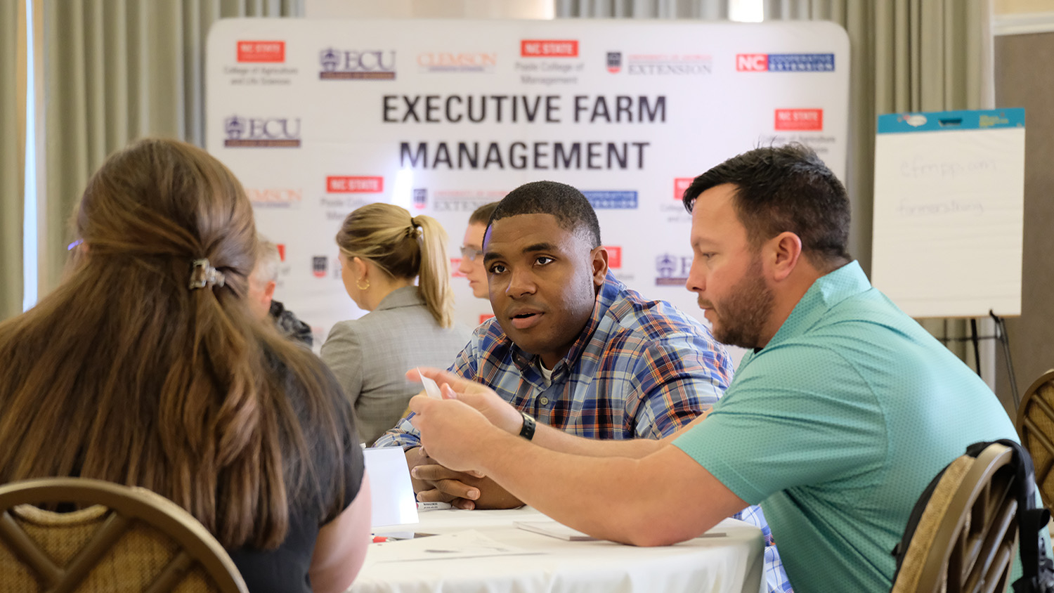 men and women sit a table with a sign behind them that says executive farm management