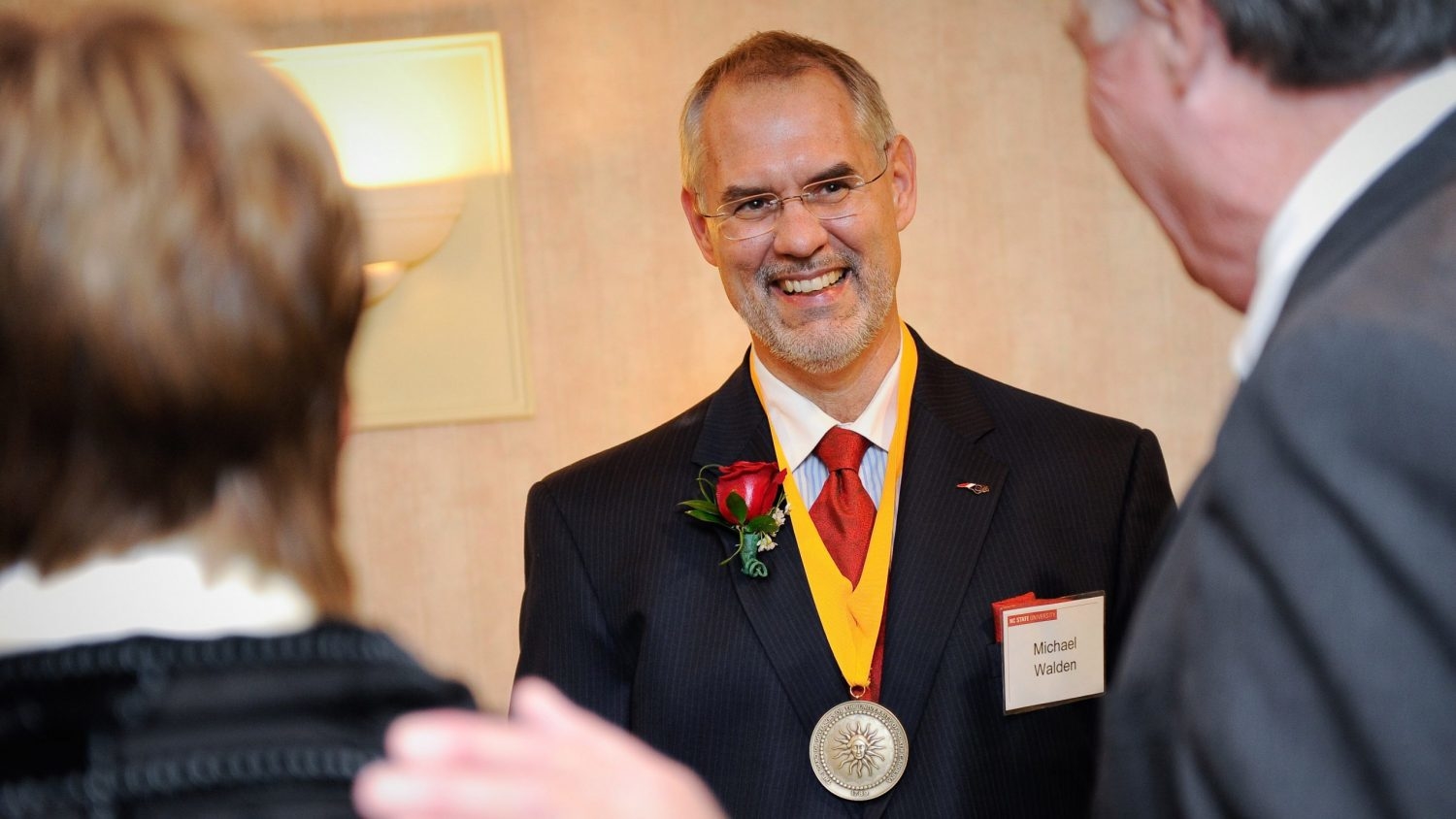 Man with medal around his neck speaking with two people