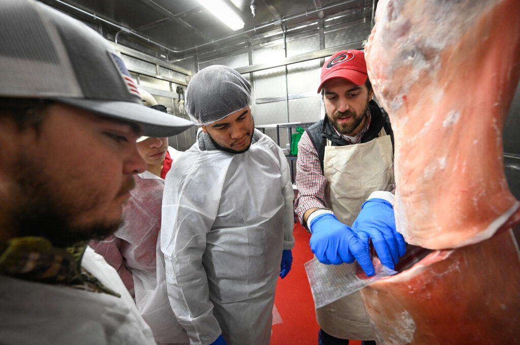 Instructor teaching students about meat processing