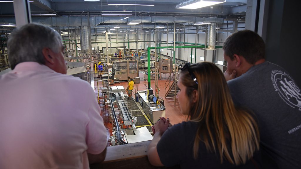 three people look at a production line from above