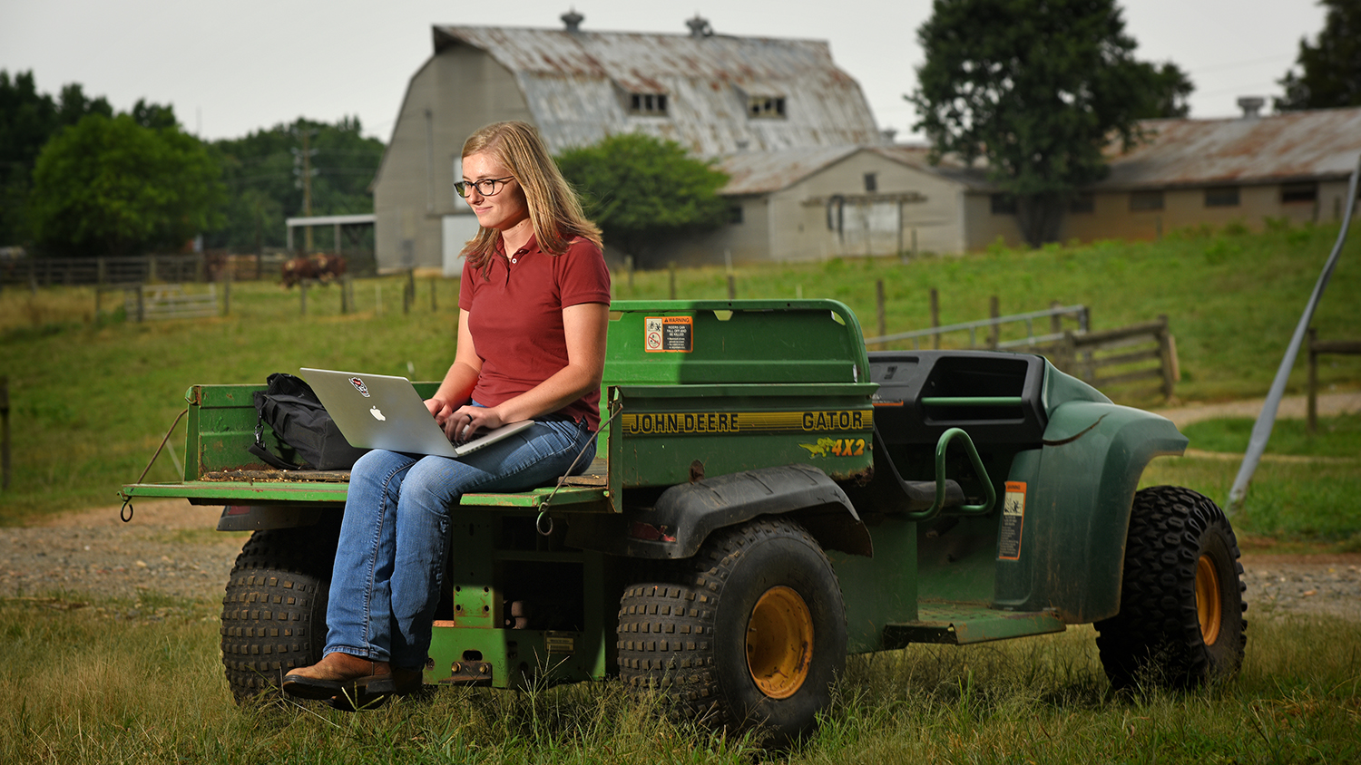 Animal Science student working on laptop sitting on a tractor.