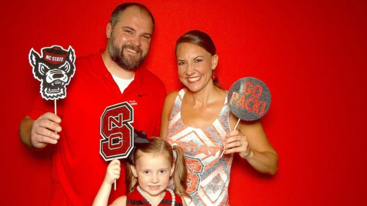 a young family holding NC State branded photo props