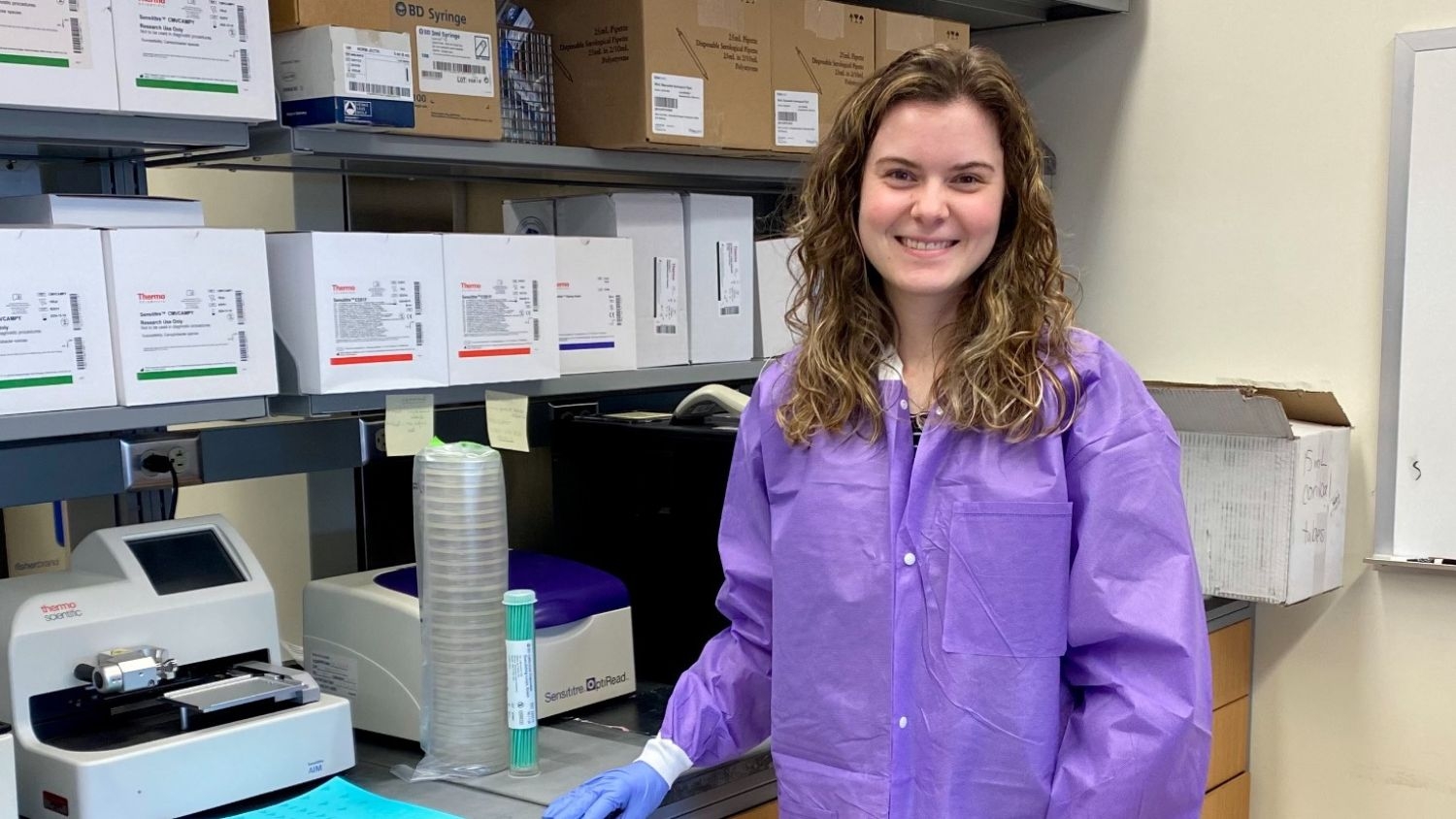 a woman scientist wearing a purple lab coat working in a lab