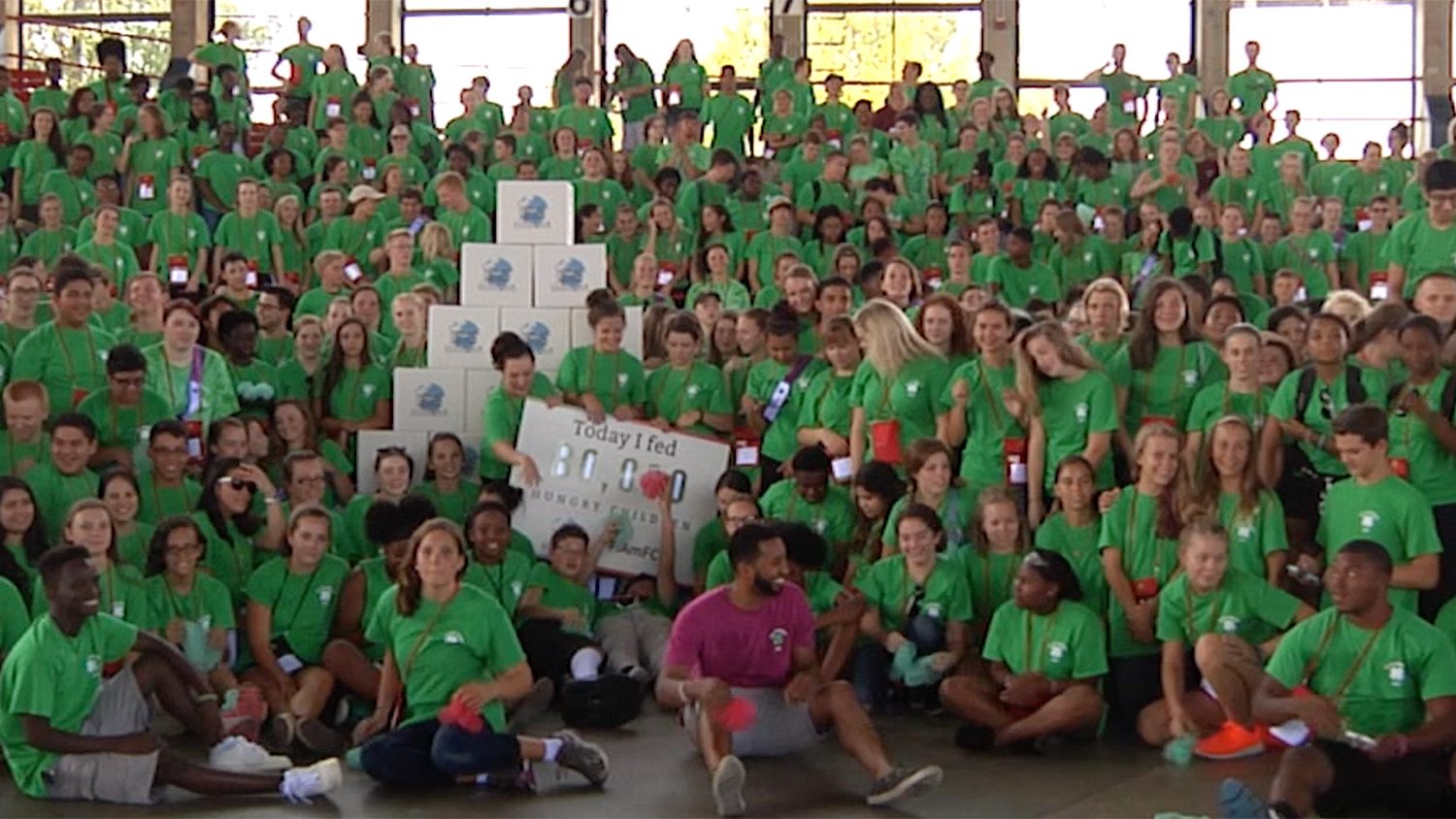 A large group of young people wearing green shirts and holding a large poster participating in the 2016 North Carolina State 4-H Congress