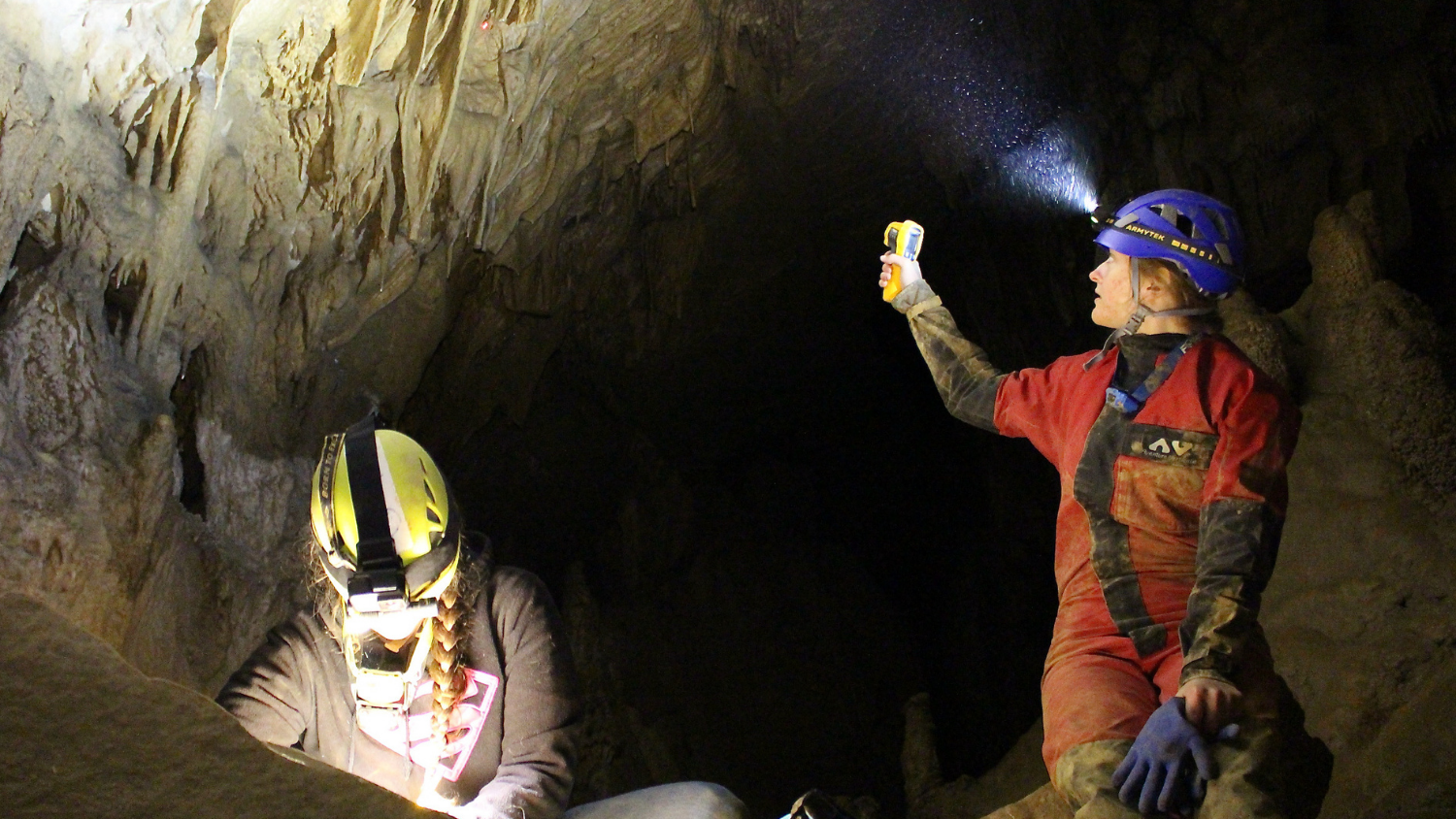 two students in a cave with headlamps
