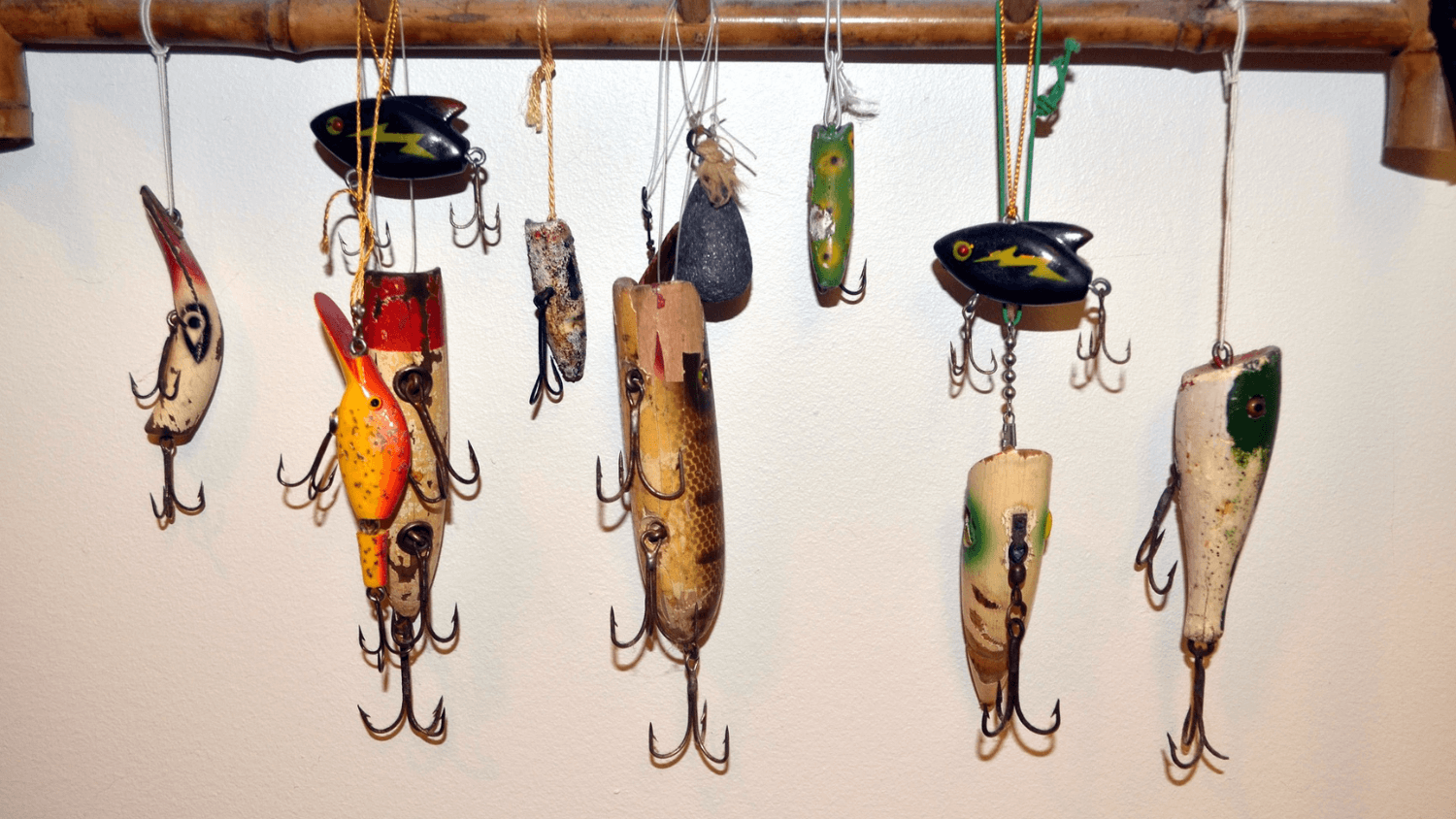 Fishing lures strung up to a wooden board