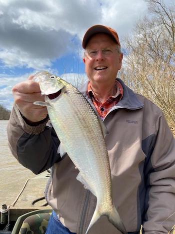 Greg Cope holds a fish in his right hand.