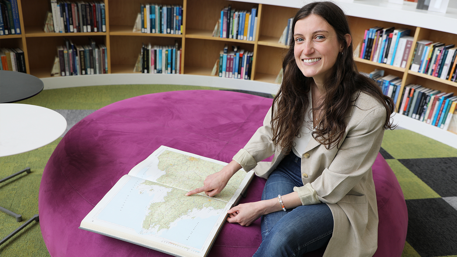 Riley Lawson sitting and pointing to France on a map