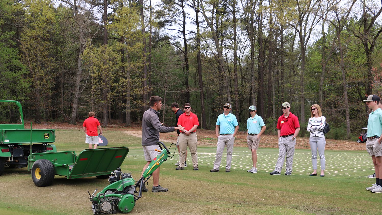 Golf course worker instructs students on equipment use