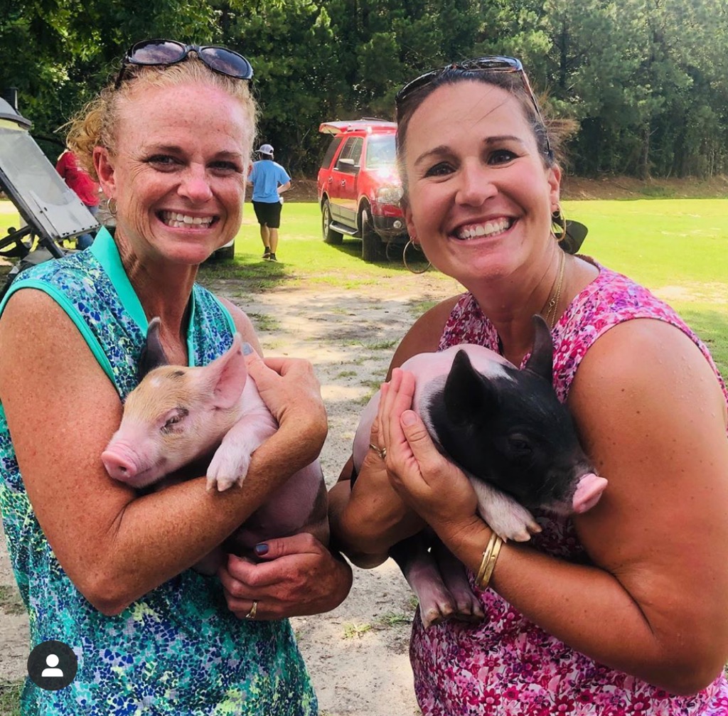Two women holding piglets at summer camp