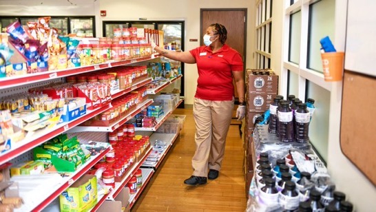 woman with mask checking food pantry shelves