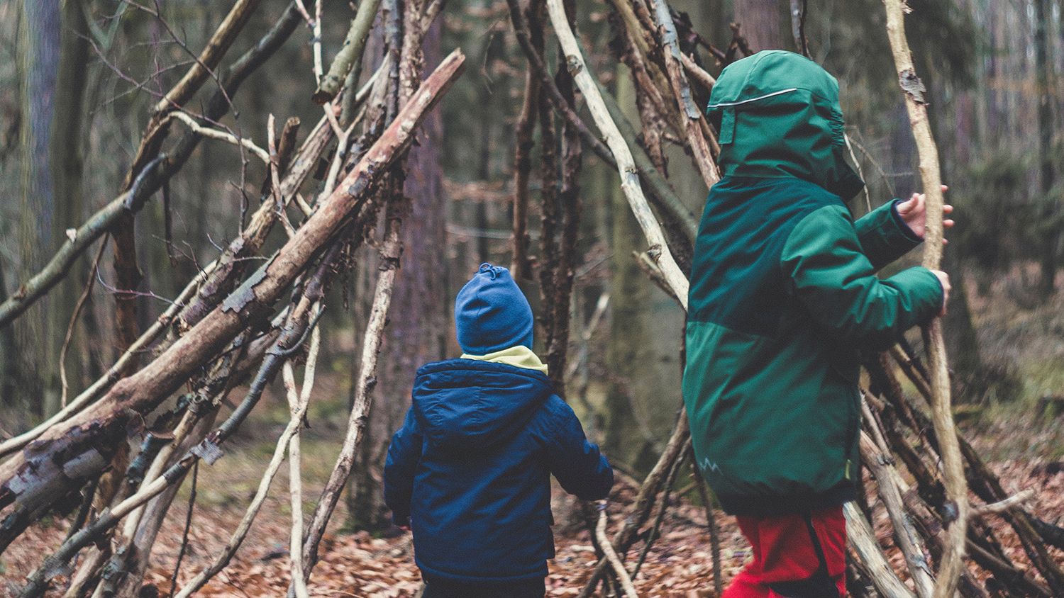 Two children building a stick structure in the woods
