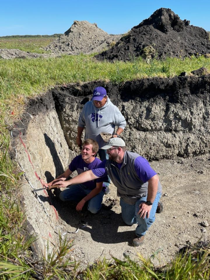 Three men evaluate a soil profile