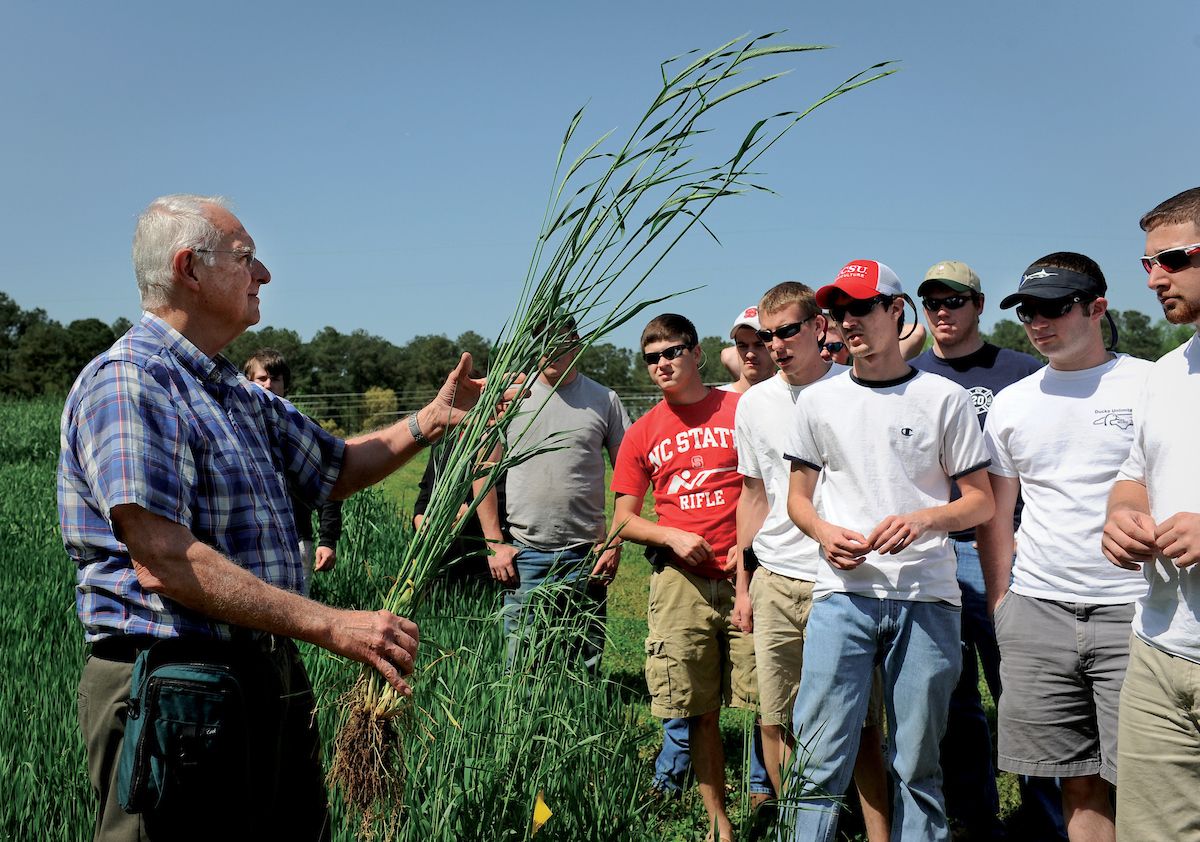 A professor shows a wheat plant to a group of agronomy students