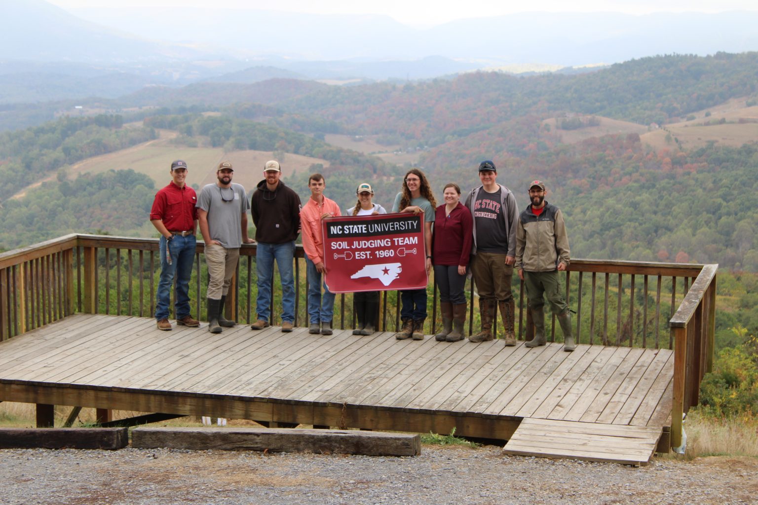 A group of students pose with an NC State soil judging team banner 