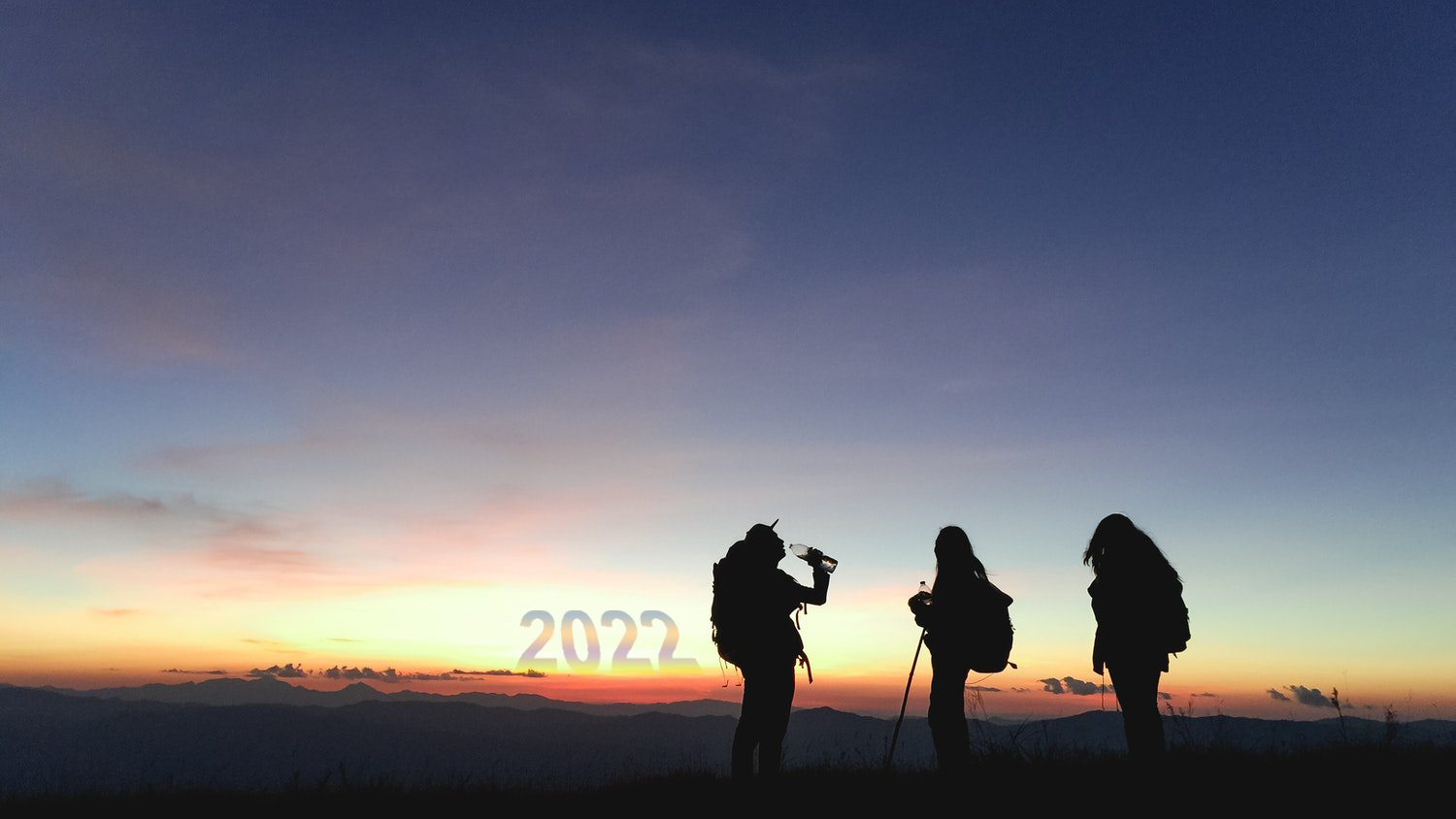 hikers stop in front of a sunrise