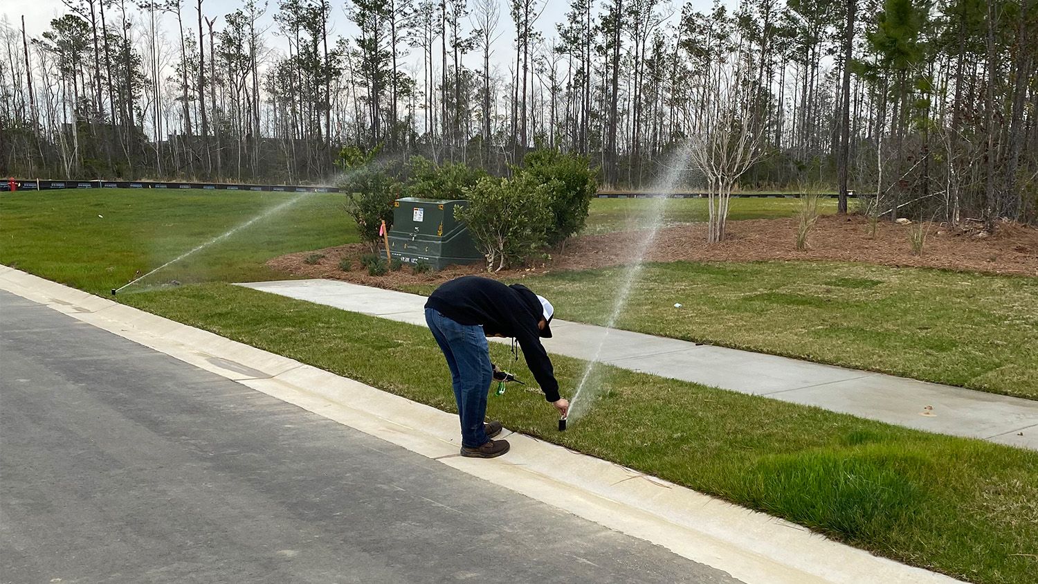 A student adjusts a turfgrass irrigation sprinkler