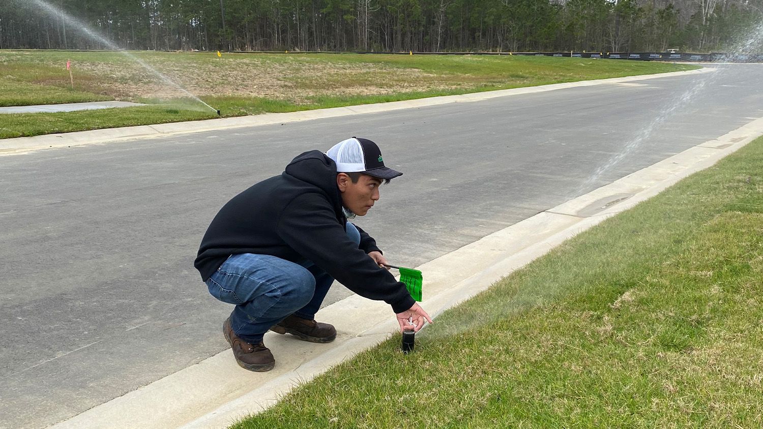 An NC State turfgrass student adjusts irrigation sprinklers