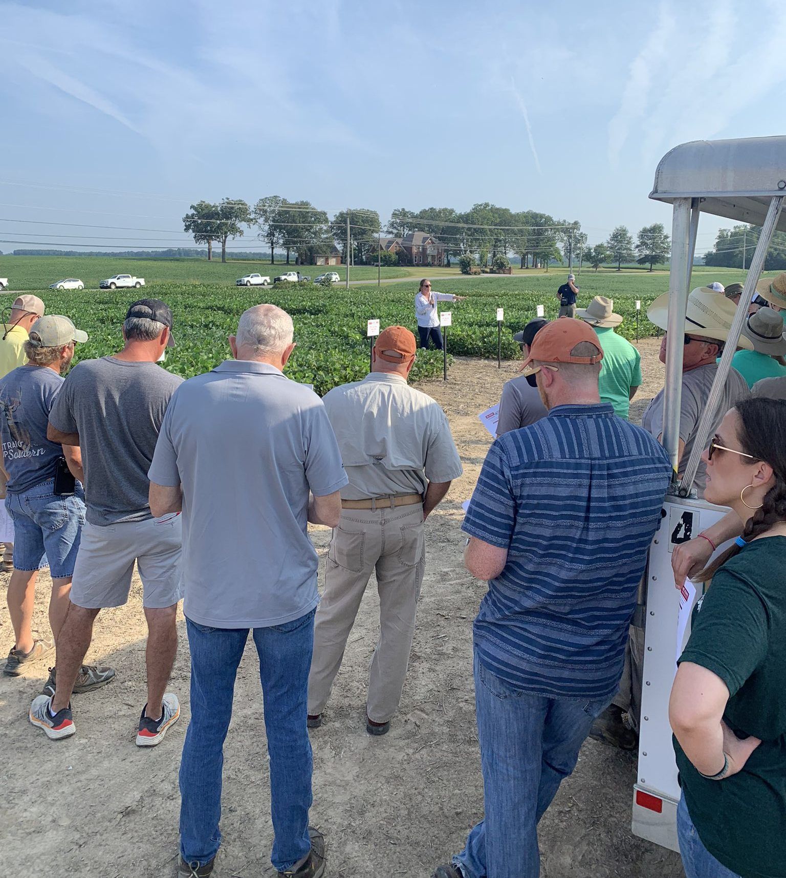 A group of farmers listen to an NC State Extension presentation at a soybean field.