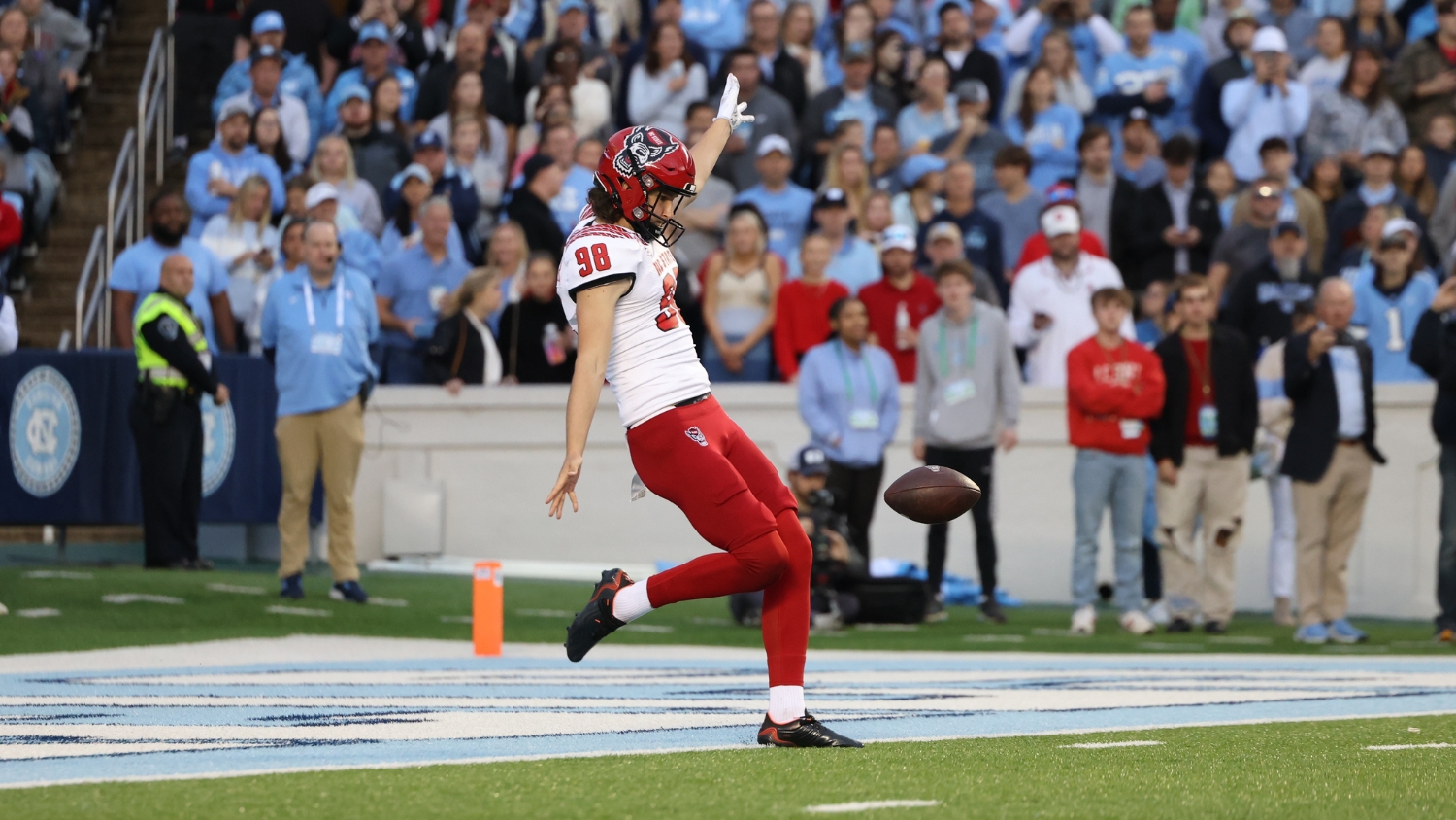 Caden Noonkester punts at an NC State vs UNC football game