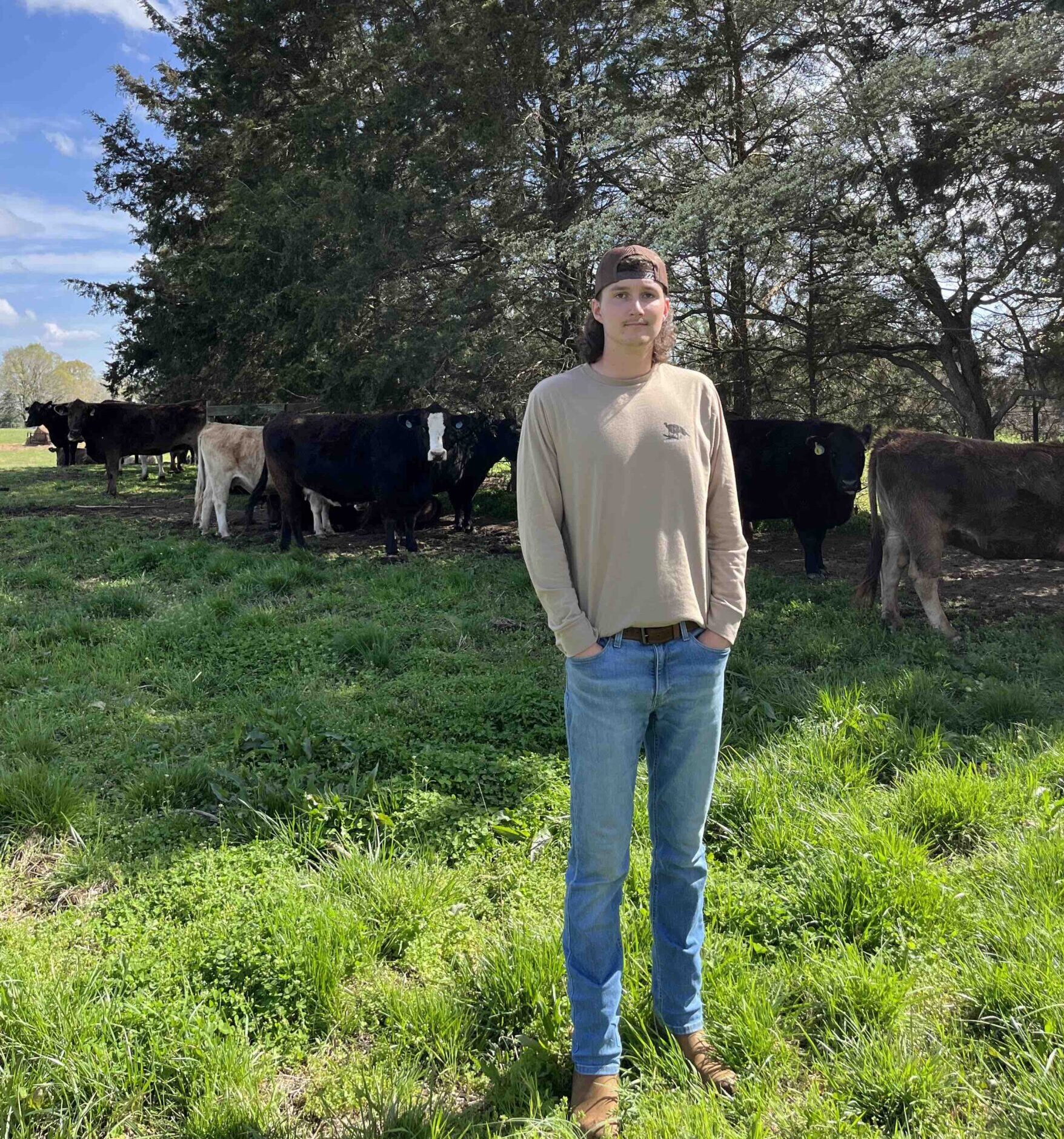 Caden Noonkester stands in a pasture with cows