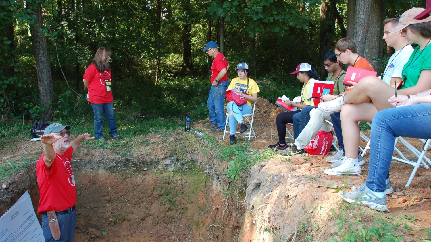 USDA NRCS David Lindbo instructs a group of Envirothon students from an NC State soil pit.