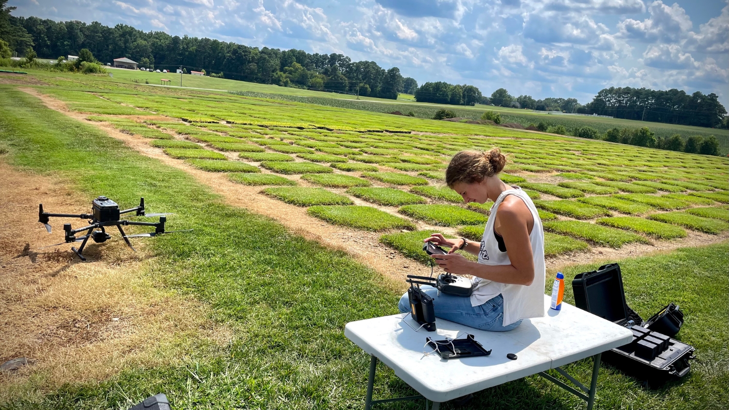 Brynna Bruxellas prepares a drone for flight at an NC State turfgrass field lab.