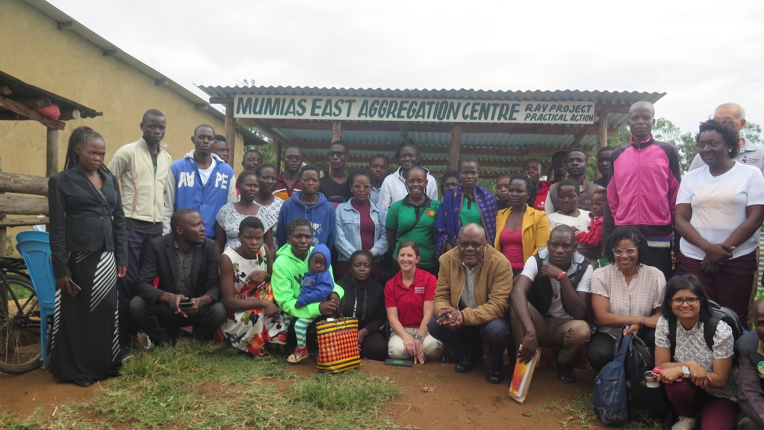 Group of people posing in front of a farm stand