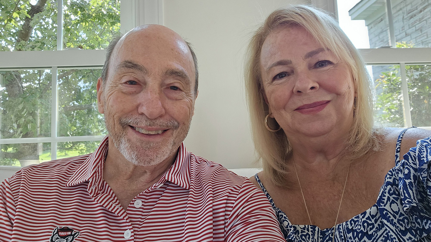 a man in a red and white striped shirt sits next to a woman in a blue and white print shirt