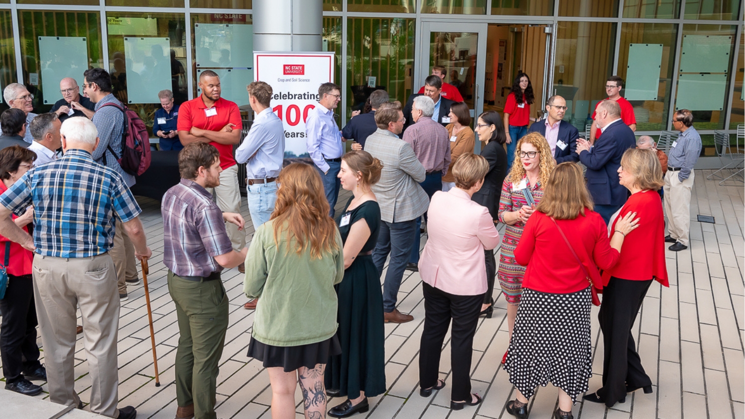 Attendees of NC State Crop and Soil Sciences 100 year anniversary celebration socialize at the N.C. Plant Sciences Building.