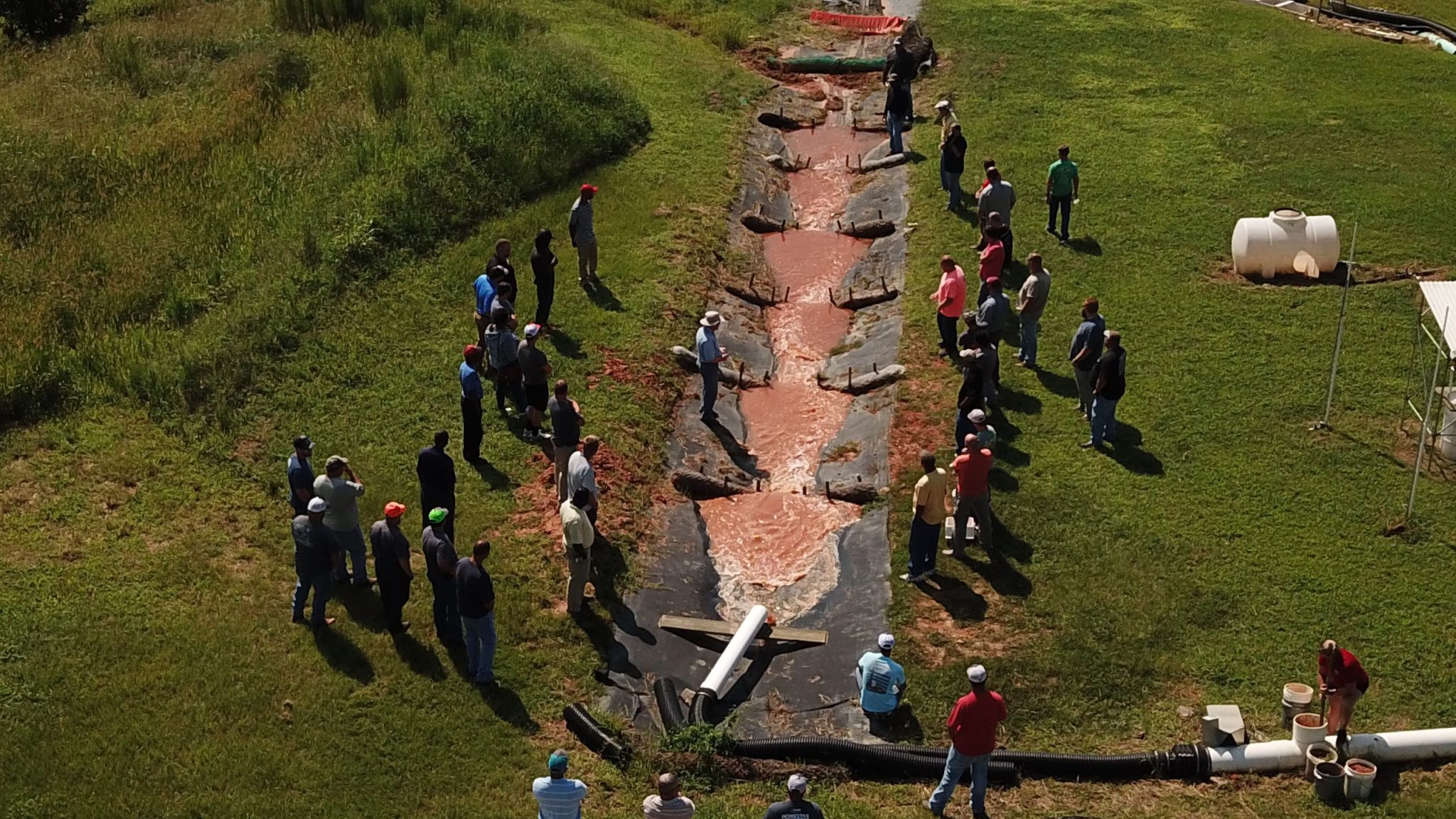 A group of soil students observe muddy water in a ditch