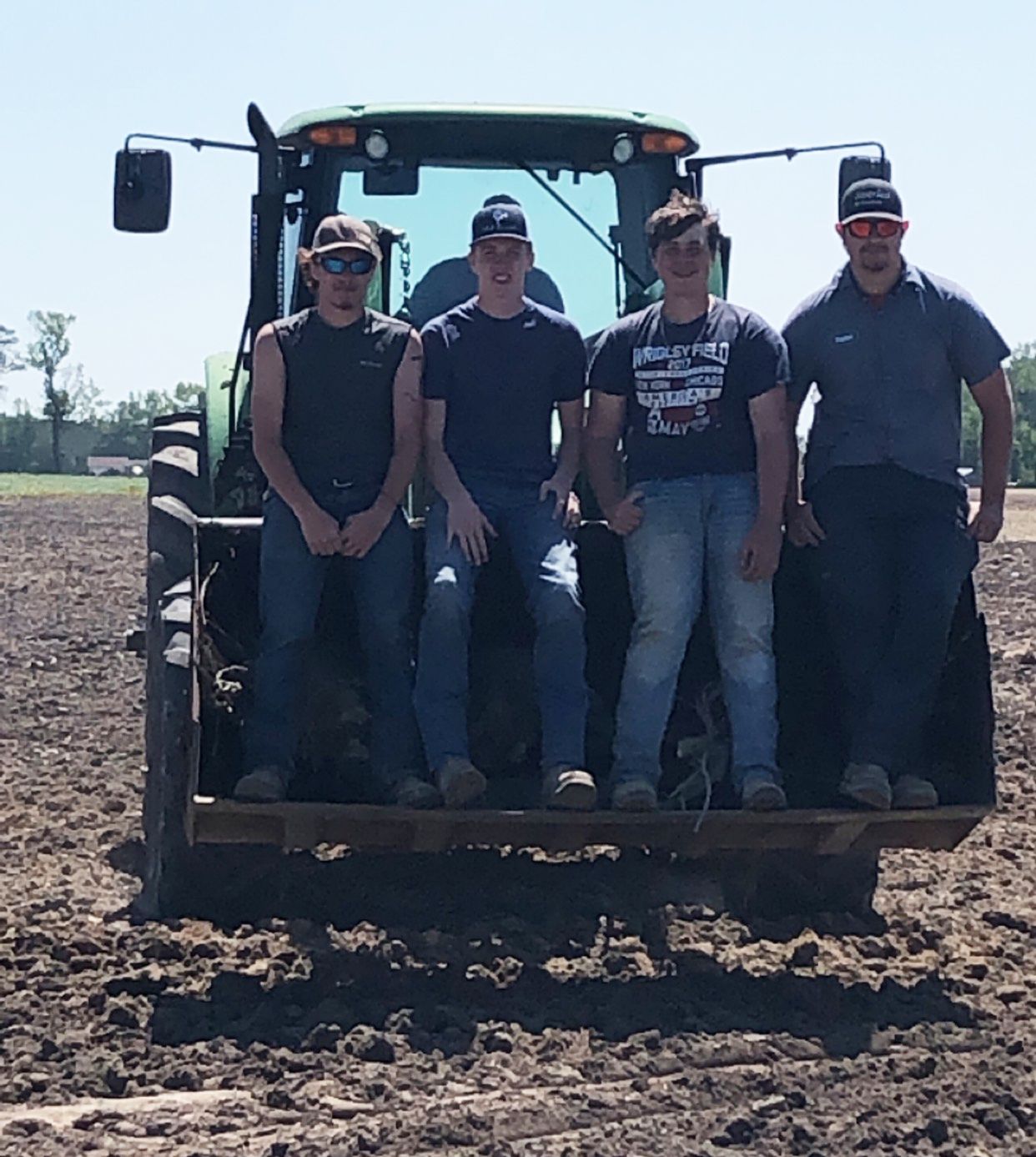 Four men standing in a tractor bucket