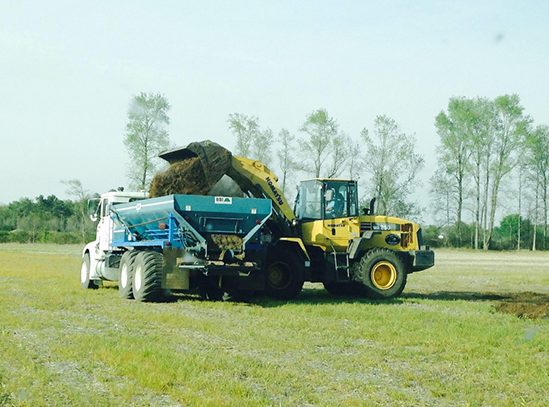 A wheel loader dumps soil into a truck bed