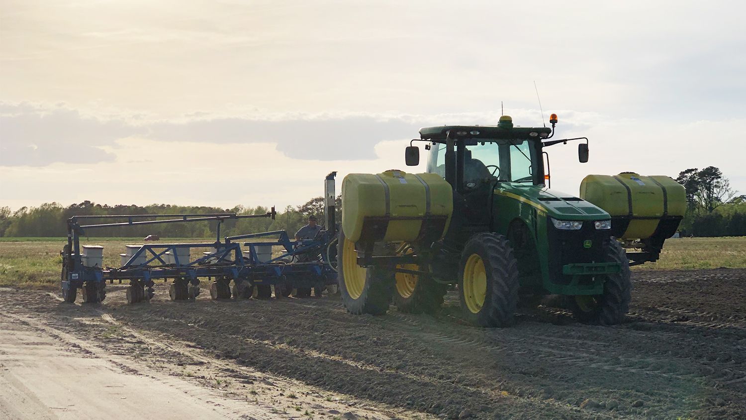 tractor pulls a planter across an empty field