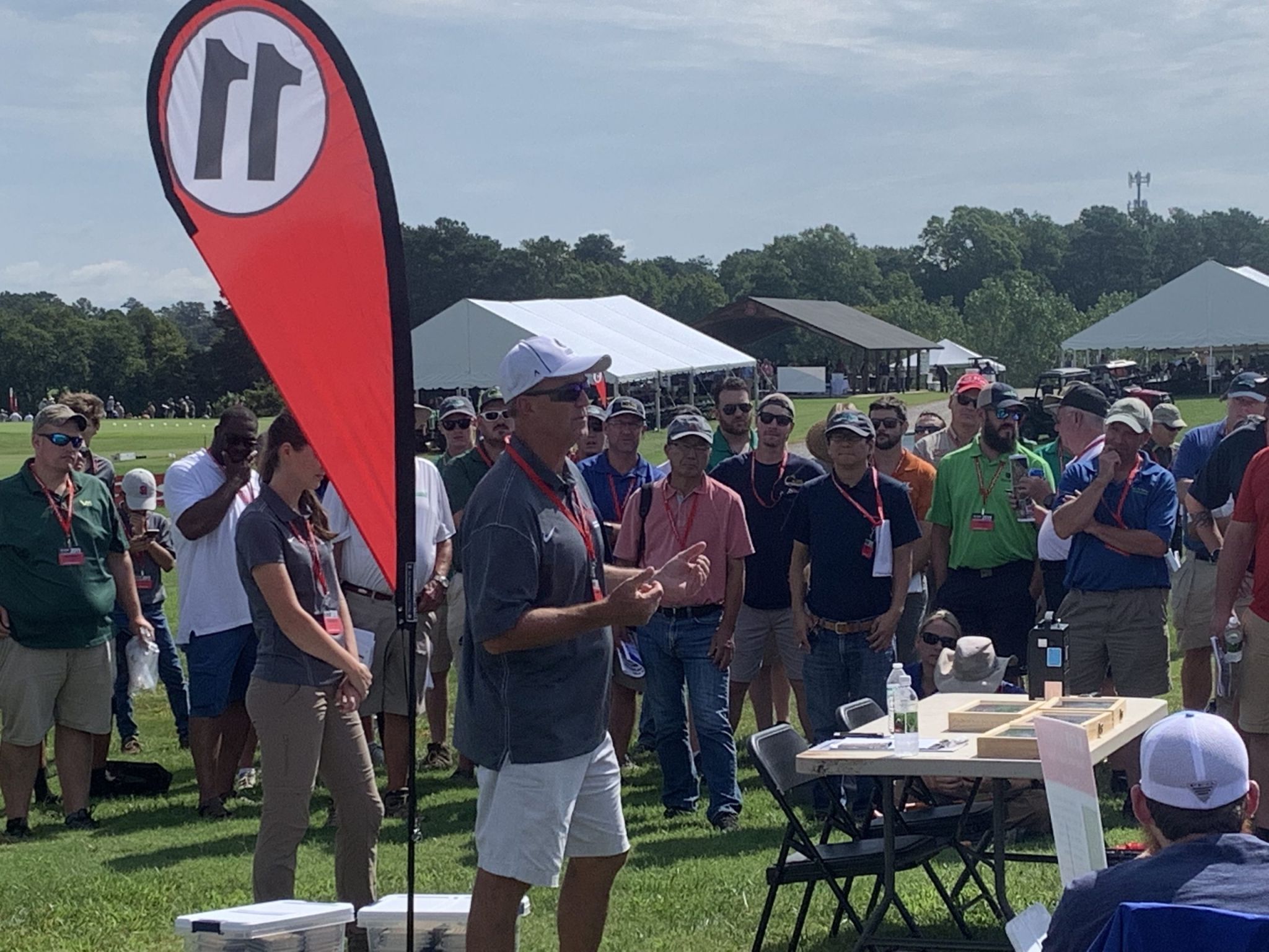 Man in cap talks at outdoor event
