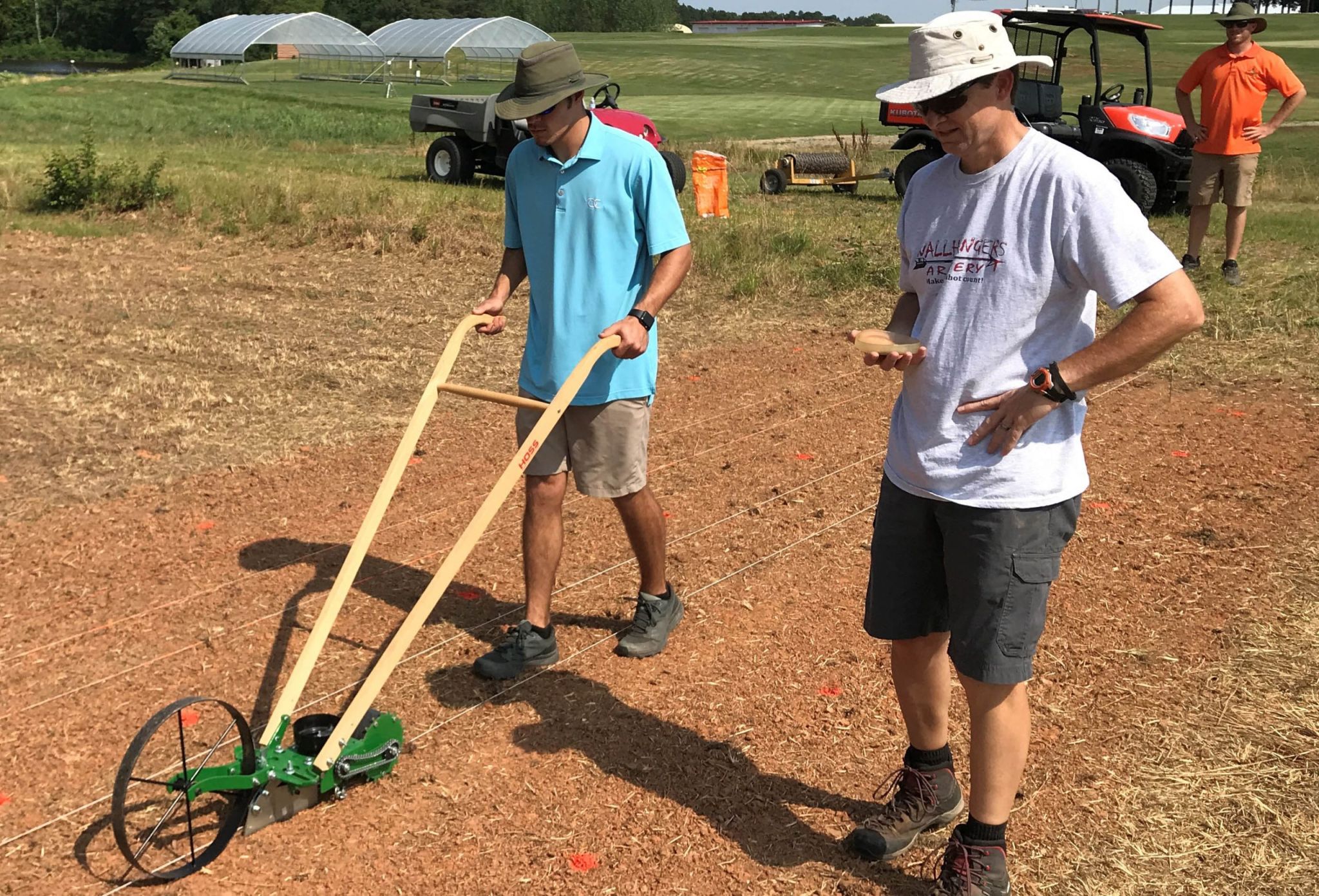 Two men spreading grass seed on bare soil