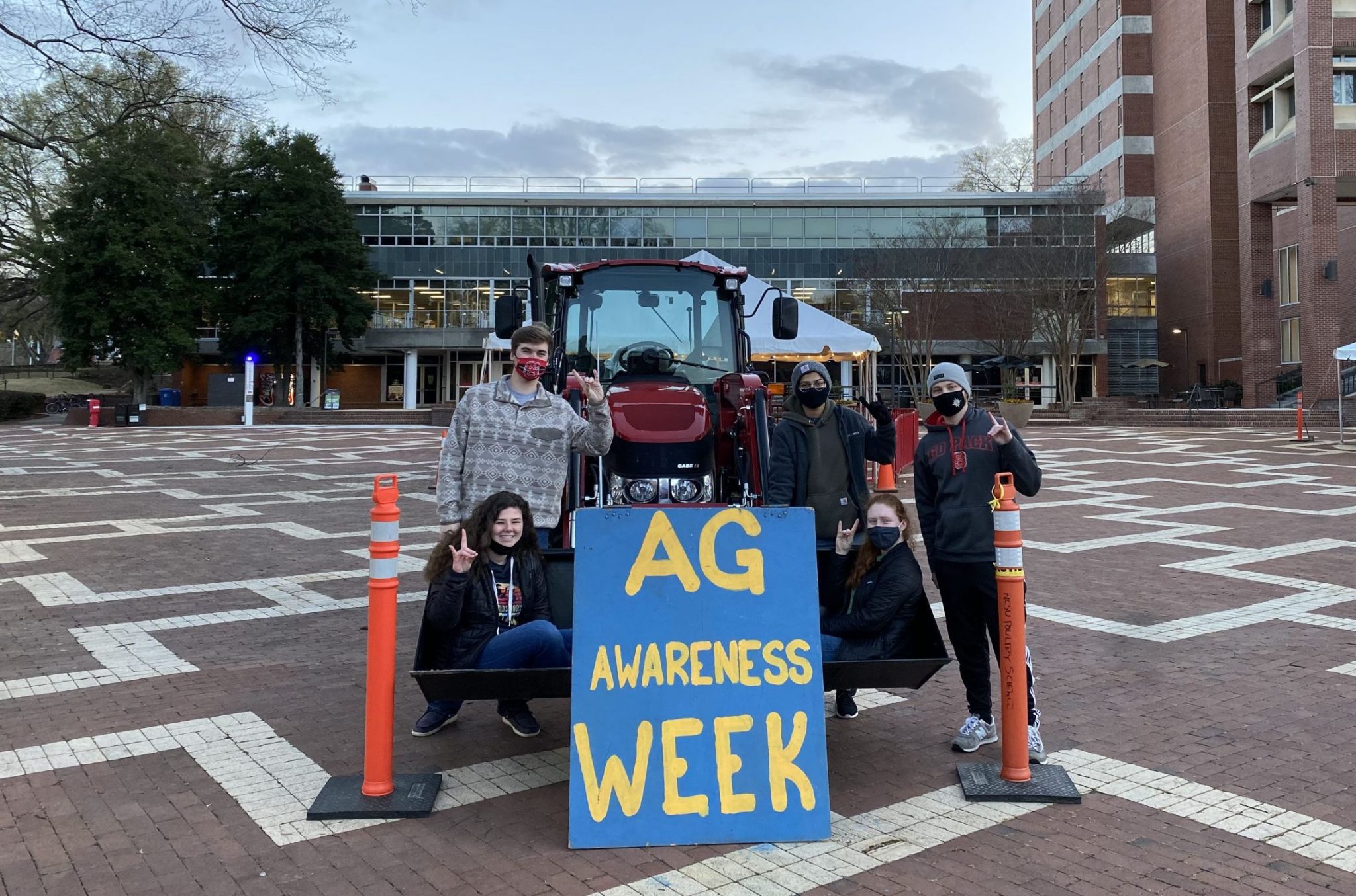 a group of students pose with a tractor on the NC State Brickyard