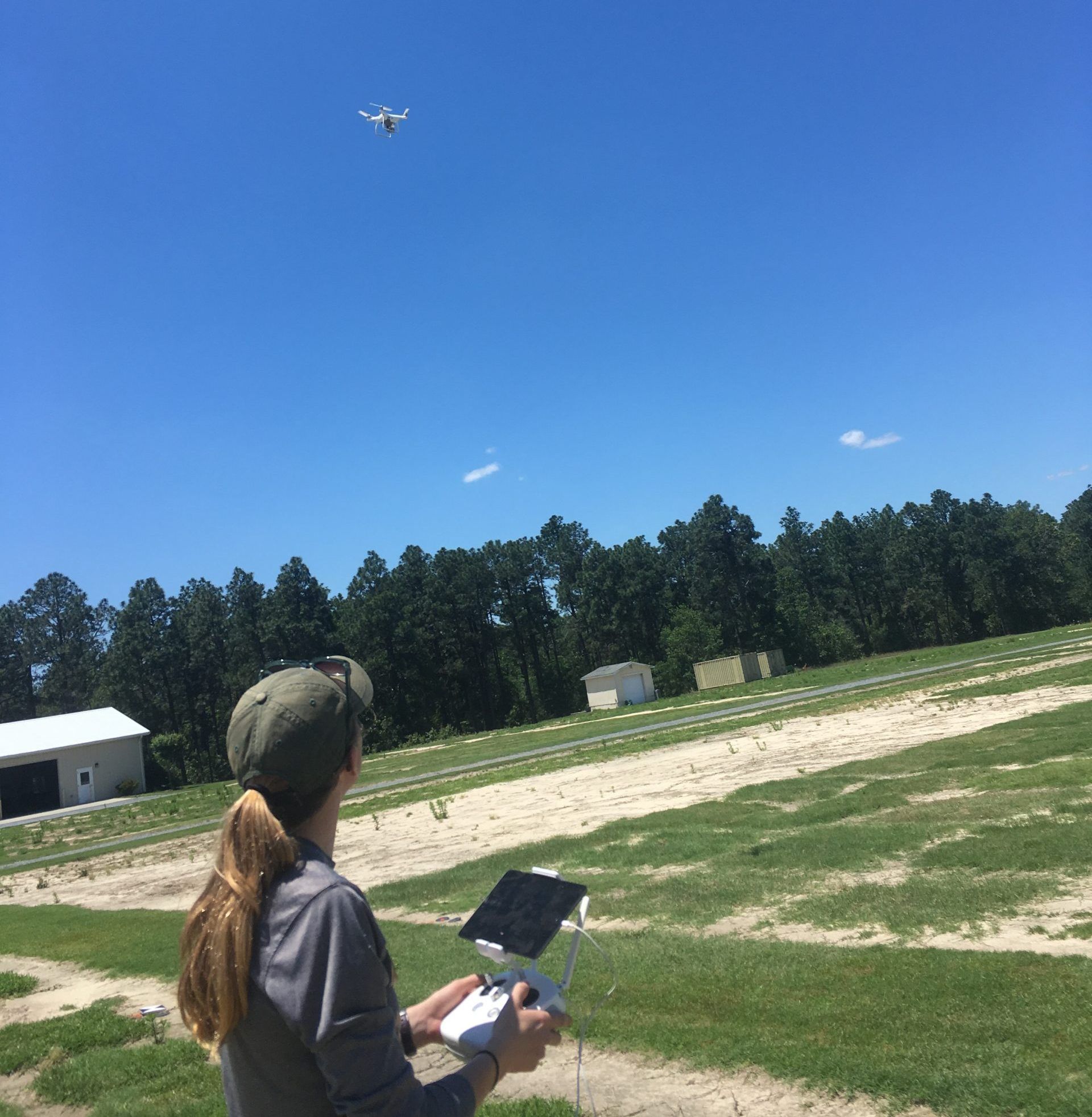 A female student flies a drone at a research field